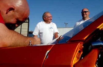 
Dan Ortiz, center, talks to Qorkey Harbison, right, of Otis Orchards in the pit, while his son-in-law, Leo Crothers, left, works on his car at Stateline Speedway Wednesday night. 
 (Kathy Plonka / The Spokesman-Review)