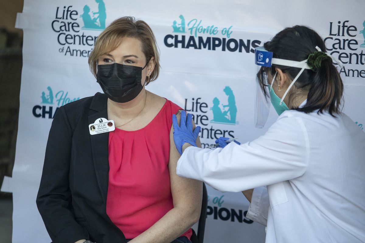 Ellie Basham, Executive Director at Life Care Center in Kirkland, Wash., being vaccinated by Kristine Kim, a pharmacist for CVS outside the Center in Kirkland, Wash., Monday, Dec. 28, 2020.  (Steve Ringman)