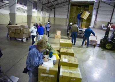 
Judy Thies checks inventory lists as Christmas Bureau volunteers unload a semitrailer load of toys at the Spokane County fairgrounds on Monday. 
 (Christopher Anderson/ / The Spokesman-Review)