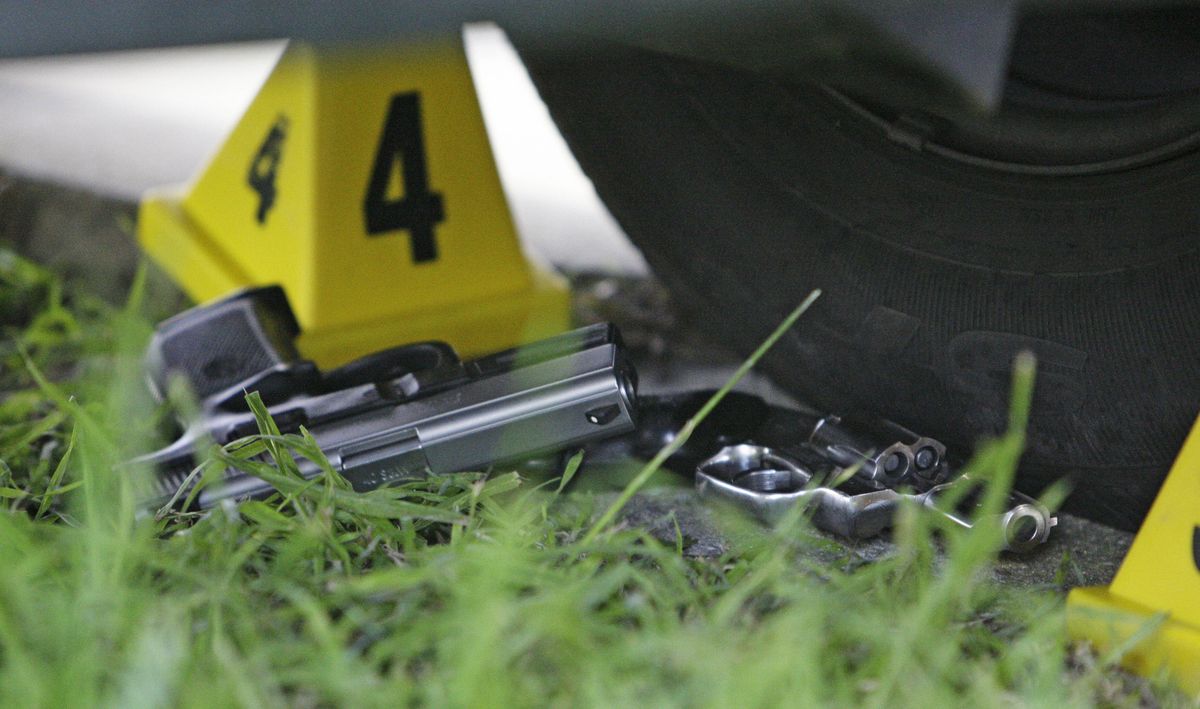 Two guns lie at the scene where five people were shot and two suspects were taken into custody in a shooting incident along the Mardi Gras parade route. (Alex Brandon / The Spokesman-Review)