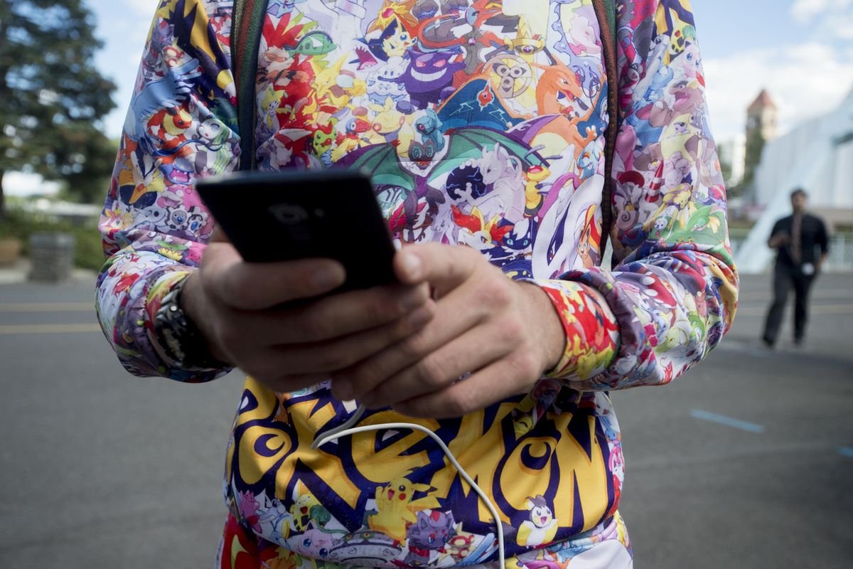 Andrew Ryan, 23, of Spokane, checks his phone for Pokemon in his vicinity while playing "Pokemon Go" on Monday, July 11, 2016, at Riverfront Park in Spokane, Wash. Already at level 17 in the popular mobile device game, Ryan came to Riverfront Park outfitted with snacks, reserve battery packs for his phone and dressed in Pokemon sweats. (Tyler Tjomsland / The Spokesman-Review)