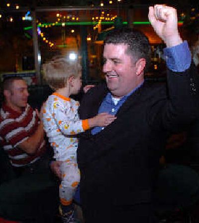 
Mike Kennedy, holding his 2-year-old son, Max, pumps his fist after Tuesday night returns show him ahead in a race for a Coeur d'Alene City Council seat. 
 (Jesse Tinsley / The Spokesman-Review)