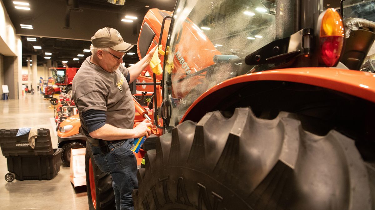Jody McBride, of Adams Tractor, cleans the windows of a Kubota tractor in the Spokane Convention Center as implement and supply dealers set up for the annual Ag Expo Monday, Feb. 4, 2019. (Jesse Tinsley / The Spokesman-Review)