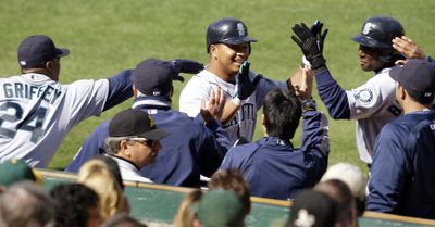 The Mariners’ Jose Lopez, center, is welcomed back to the dugout after scoring on a Kenji Johjima single in the eighth inning. (Associated Press / The Spokesman-Review)