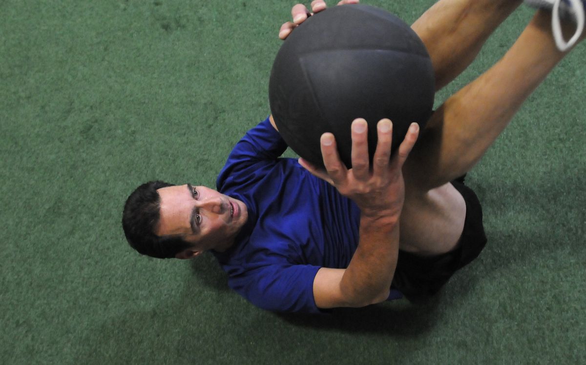 The Spokesman-Review Mike Sacco, who is still recovering from severe injuries he received when he was struck by a car, works out with a medicine ball at Champions Physical Therapy recently. He believes his fitness routine staves off severe back pain from his injuries. (Jesse Tinsley / The Spokesman-Review)