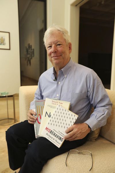 In this photo provided by the University of Chicago, Richard Thaler poses for a photo with his books at his home in Chicago after winning the Nobel prize in economics, Monday, Oct. 9, 2017. (Anne Ryan / Associated Press)