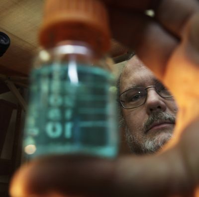 David Baldwin, a research zoologist with NOAA Fisheries, holds a vial of copper chloride solution earlier this month  in his Seattle lab.  (Associated Press)