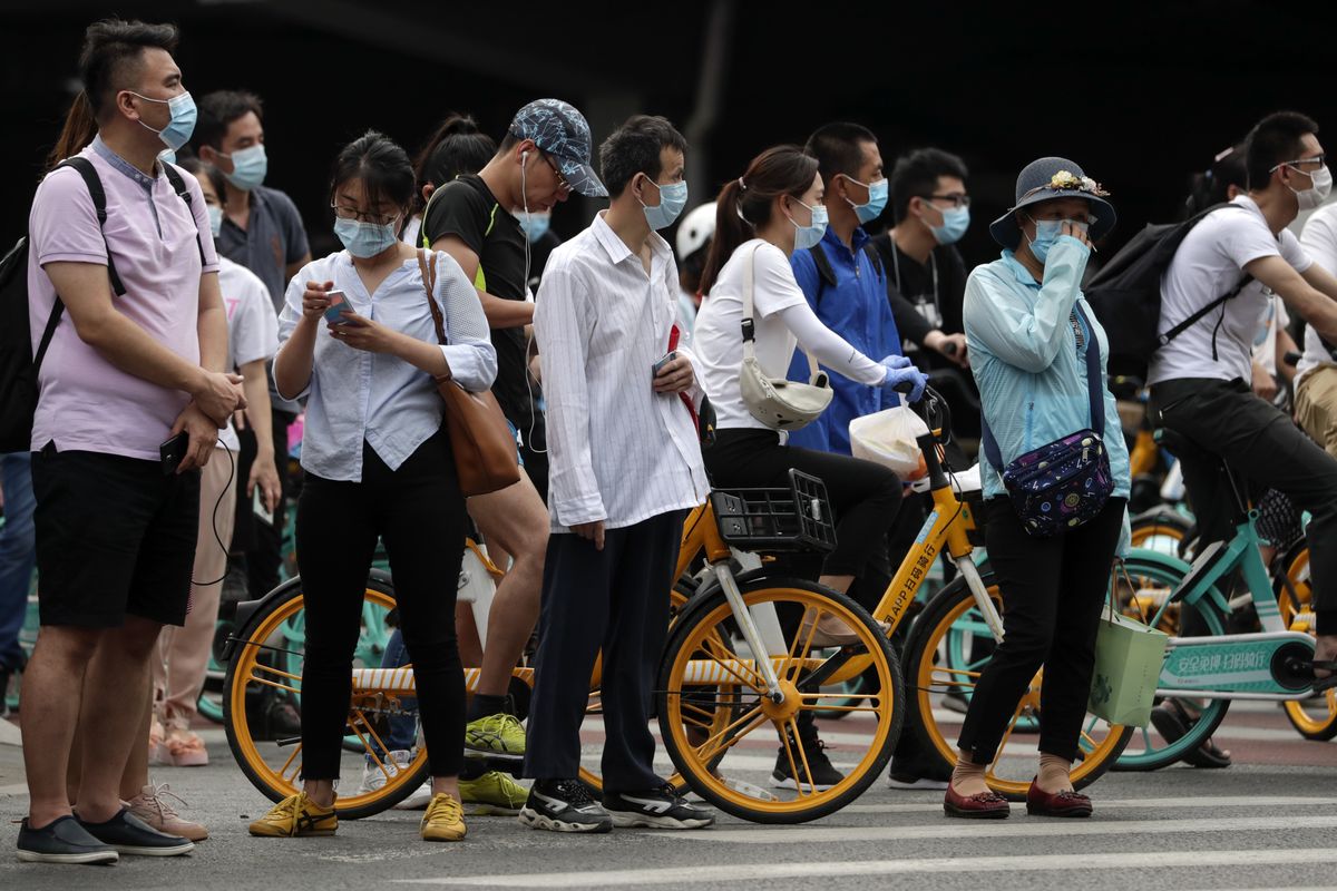 People wearing protective face masks to help curb the spread of the new coronavirus wait to cross a street in Beijing, Monday, June 22, 2020. A Beijing government spokesperson said the city has contained the momentum of a recent coronavirus outbreak that has infected a few hundreds of people, after the number of daily new cases fell to single digits.  (Andy Wong)