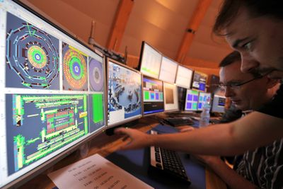 Scientists control computer screens showing traces of the first protons injected into the Large Hadron Collider during its switch-on operation, at the press center  Wednesday near Geneva.  (Associated Press / The Spokesman-Review)