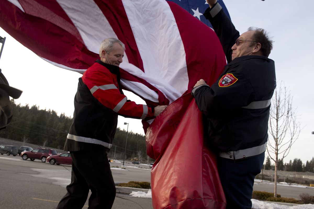 After the funeral of Sgt. Jacob Hess, Dave Leavenworth, left, and Doug Dodson of the Spokane Fire Department take down the department’s giant flag, which was put up to honor the Marine who died in Afghanistan on New Year’s Day. The funeral was Monday. (Jesse Tinsley)
