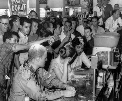 In this May 28, 1963 photo, a group of whites pour sugar, ketchup and mustard over the heads of Tougaloo College student demonstrators at a sit-in demonstration at a Woolworth’s lunch counter in Jackson, Miss. Seated at the counter, from left, are Tougaloo College professor John Salter, and students Joan Trumpauer and Anne Moody. (Fred Blackwell / Associated Press)