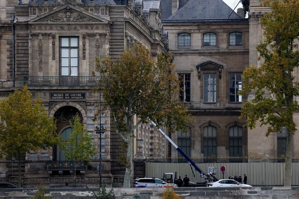 Police officers work next to a crane and a window believed to have been used in what the French Interior Ministry said was a robbery Sunday at the Louvre museum during which jewelry was stolen in Paris.  (Reuters )