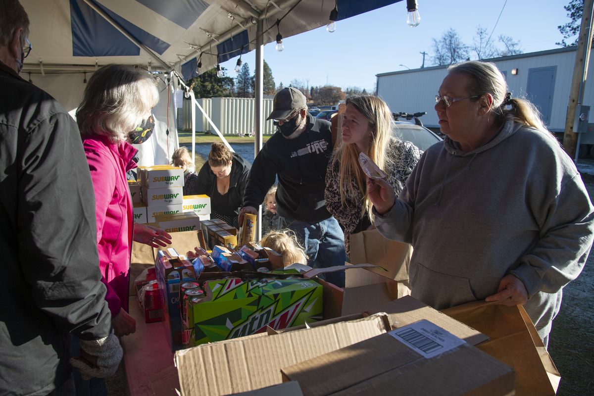 Rev. Kathy Lamphere, left, greets local residents at a tent in Malden City Park and offers a free lunch sponsored by the Episcopal Diocese of Spokane, Wednesday, Dec. 2, 2020. The small Whitman County town destroyed by fire on Labor Day of this year is still struggling to get recovery and rebuilding efforts underway and families are still struggling to get basic needs met. A variety of charitable groups have helped the town by serving lunches, donating clothes and housewares, as well as cash. Lamphere pastors in Cheney and was in Malden representing the Episcopal Diocese.  (Jesse Tinsley/The Spokesman-Review)