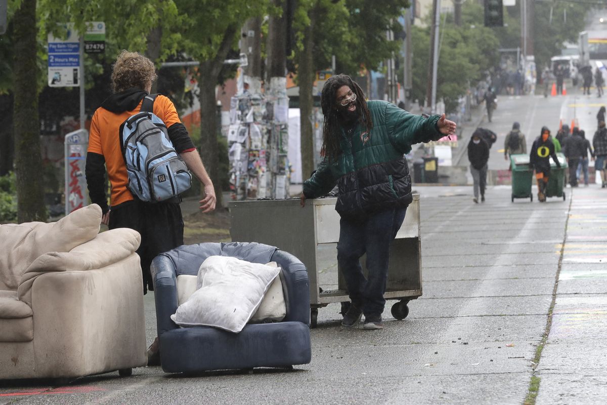 Protesters move items in place to block the street after Seattle Department of Transportation workers removed concrete barricades at the intersection of 10th Ave. and Pine St., Tuesday, June 30, 2020 at the CHOP (Capitol Hill Occupied Protest) zone in Seattle. The area has been occupied by protesters since Seattle Police pulled back from their East Precinct building following violent clashes with demonstrators earlier in the month.  (Ted S. Warren)