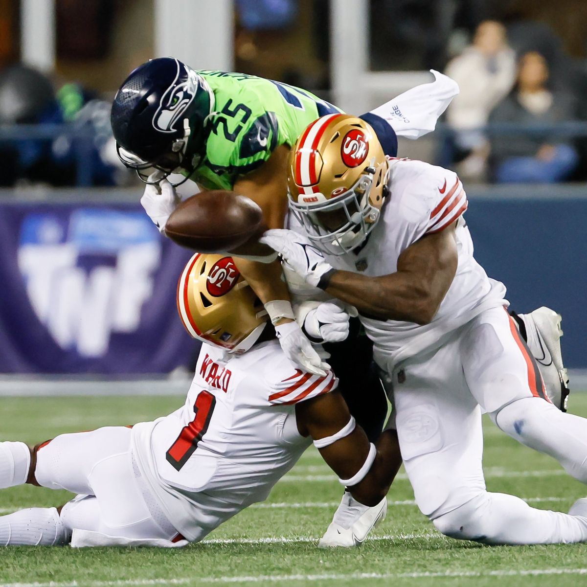 San Francisco linebacker Dre Greenlaw, right, hits Seattle running back Travis Homer as he is tackled by cornerback Charvarius Ward, causing a fumble during the second quarter Thursday at Lumen Field in Seattle. The 49ers won 21-13.  (Jennifer Buchanan)