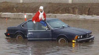 
A resident of Ontario in Southern California waits for assistance as she is stranded in a flooded city intersection Tuesday after a heavy storm hit the area. 
 (Associated Press / The Spokesman-Review)