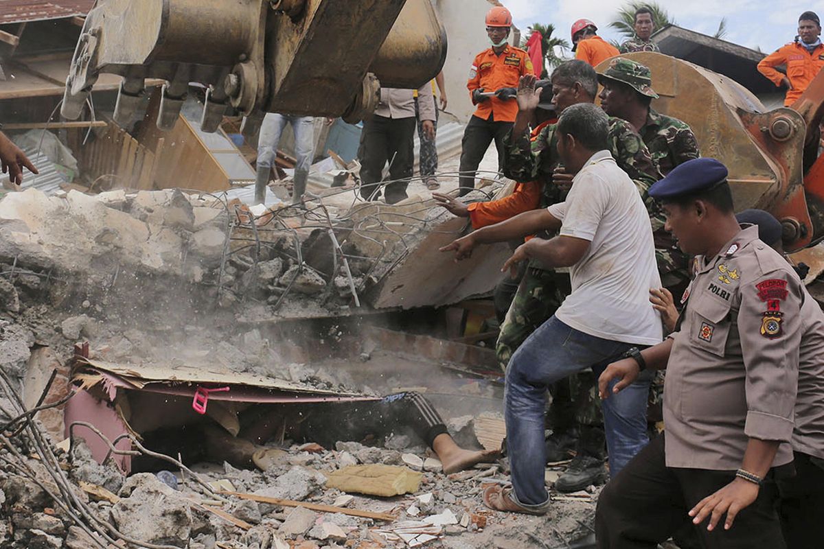 Rescuers recover the body of a victim from a collapsed building after an earthquake in Pidie Jaya, Aceh province, Indonesia, Wednesday. (Heri Juanda / Associated Press)