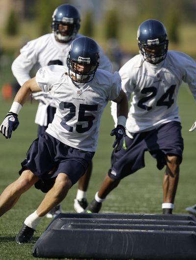 Brian Russell (25) and Deon Grant (24) run through a drill at training camp. (Associated Press / The Spokesman-Review)