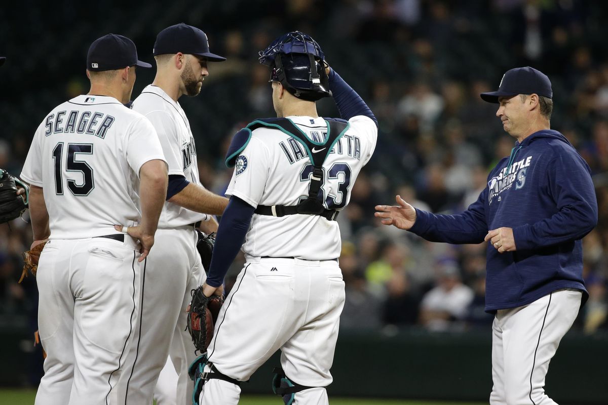 Seattle Mariners manager Scott Servais, right, reaches to take the ball from starting pitcher Nathan Karns, left rear, as Karns is pulled during the sixth inning Tuesday. (Ted S. Warren / Associated Press)