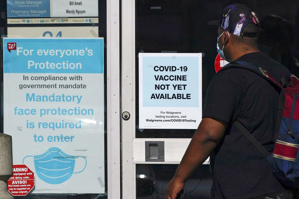 A customer walks past a sign indicating that a COVID-19 vaccine is not yet available at Walgreens on Wednesday in Long Beach, Calif.  (Ashley Landis)