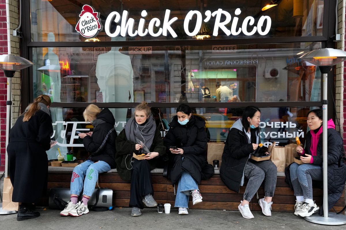 People eat their takeaway food sitting outside a cafe that is closed due to the coronavirus in Moscow, Russia, on Oct. 29. (Alexander Zemlianichenko)