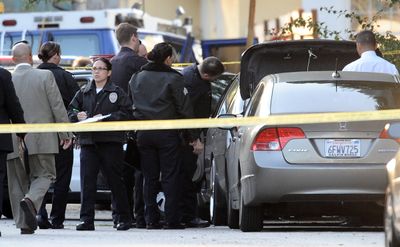 Police detectives investigate the scene where a woman’s body was found dead in the trunk of a car in Los Angeles on Saturday.  (Associated Press / The Spokesman-Review)