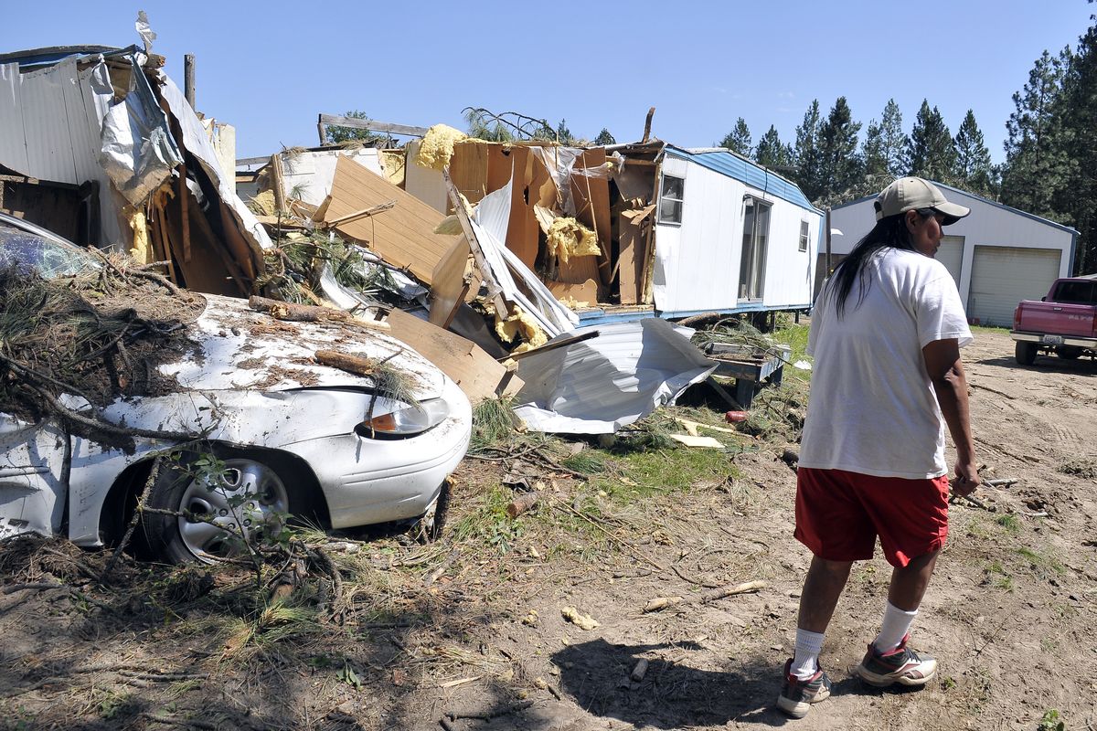 Terri Covington walks past what is left of her car and mobile home near Keller, Wash., on Friday. (Jesse Tinsley)
