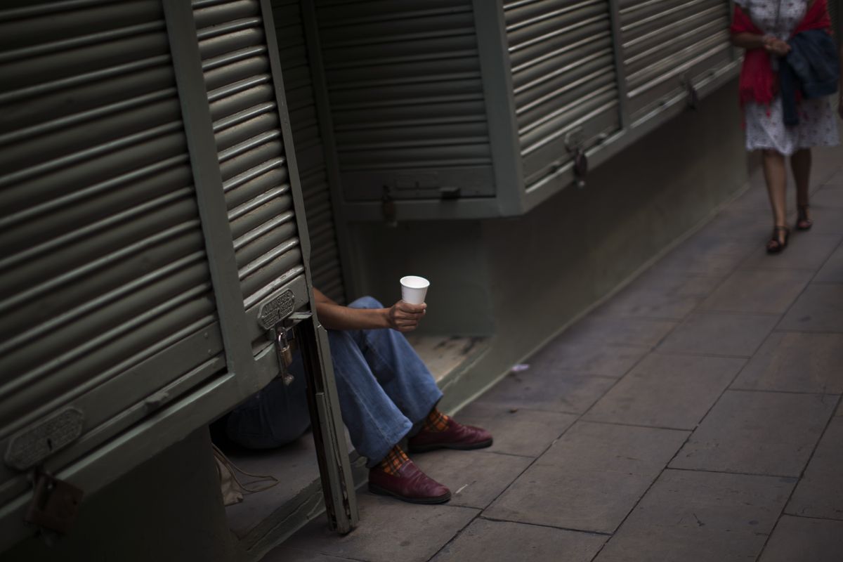A man begs in Barcelona on Saturday. Spain has asked for a bank bailout from the eurozone. (Associated Press)
