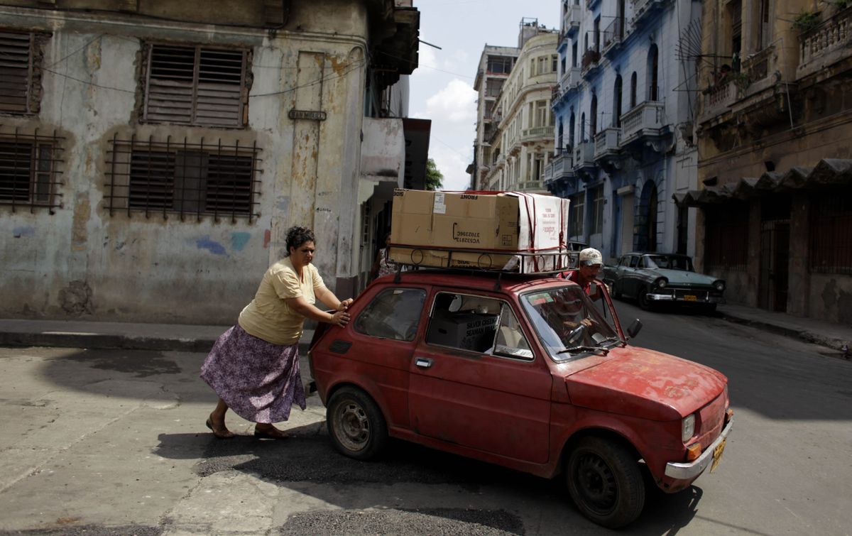 A couple push a car Monday in Havana. President Barack Obama is allowing Americans to make unlimited trips and money transfers to relatives in Cuba. (Associated Press / The Spokesman-Review)