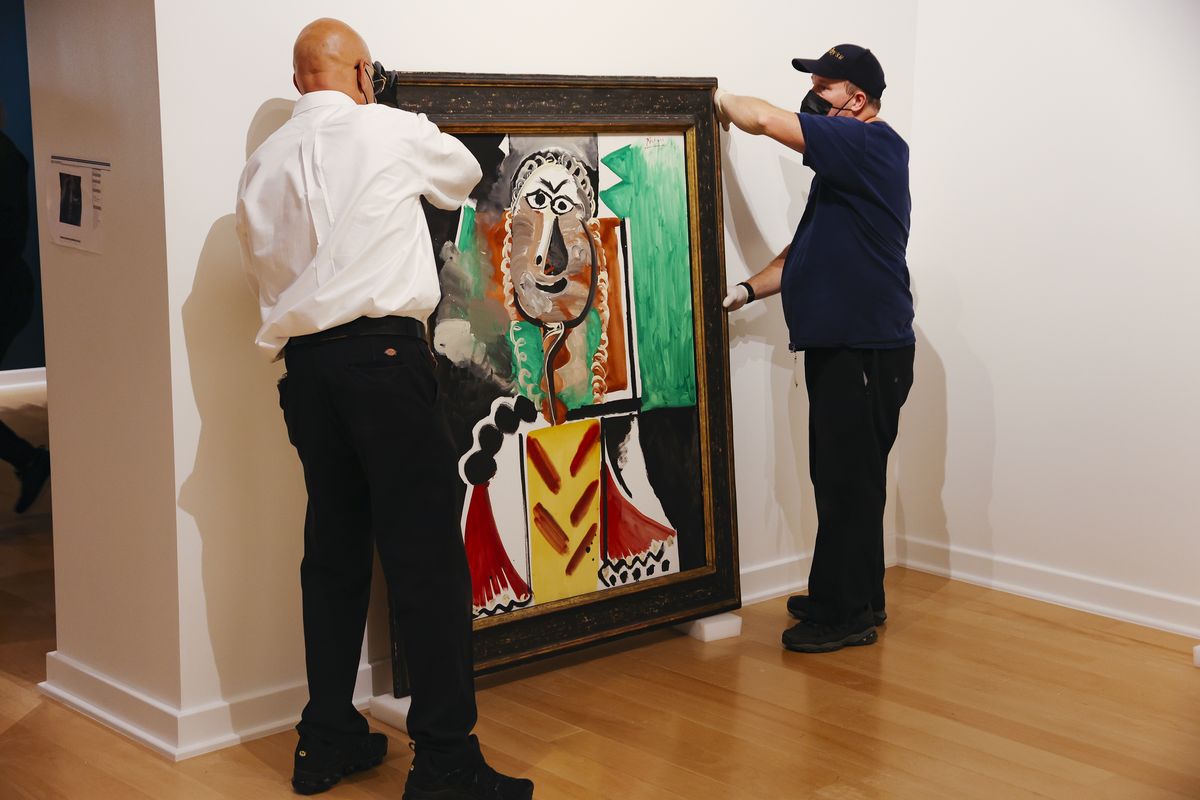 From left, Jose Reynoso and Terence McAllister lift a still life painting by Pablo Picasso titled "Buste d'Homme" at the Bellagio Gallery of Fine Art Tuesday, Oct. 19, 2021 in Las Vegas. The artworks — nine are paintings and two are ceramic pieces — are part of MGM Resorts' collection and will be offered at auction Saturday.  (Wade Vandervort)