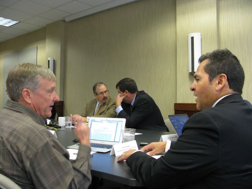 Idaho insurance exchange board Chairman Stephen Weeg and member Jim Rice confer, center; at left foreground is board member Kevin Settles, at right, member Fernando Veloz. (Betsy Russell)