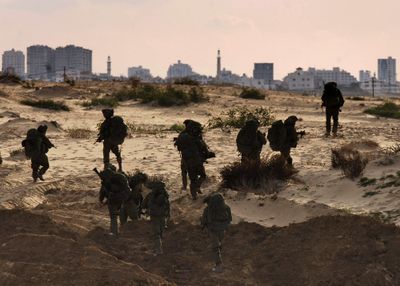 In this photo released by the Israeli army, Israeli soldiers walk toward the northern Gaza Strip, as seen from Israel’s border with Gaza, on Monday.  (Associated Press / The Spokesman-Review)