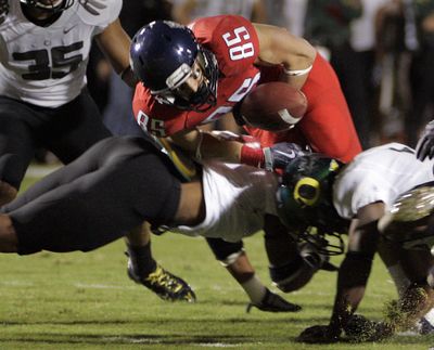 Arizona’s David Douglas fumbles the ball after being hit by Oregon’s T. J. Ward, bottom, in the first half. (Associated Press)