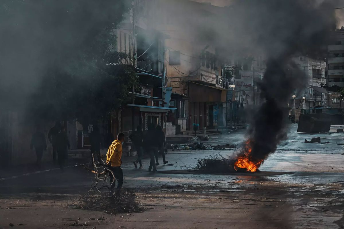 Young men place obstacles to try to block Israeli army vehicles from cruising through a street during Israeli raids in Jenin, in the West Bank, and its refugee camp in December 2023.  (Marcus Yam/Los Angeles Times/TNS)