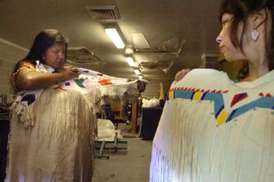 
Lori Sijohn, left, and her sister Lisa Hungary talk at Julyamsh on Saturday about why they wear their buckskin dresses in the dance arena. They prepared for the day's events in a storage area reserved for participants with horses. 
 (Photos by JESSE TINSLEY / The Spokesman-Review)