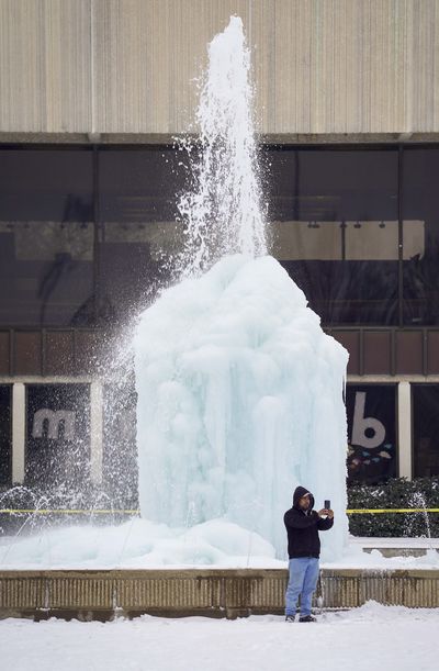 In this photo from Feb. 17, 2021, Carlos de Jesus takes a selfie in front of the frozen fountain at the Richardson Civic Center after a second winter storm brought more snow and continued freezing temperatures to North Texas in Richardson, Texas. After watching the fountain freeze over the past few days, de Jesus, who lives nearby, said he decided to take a photo Wednesday on his way home from work.    (Smiley N. Pool/The Dallas Morning News/TNS)
