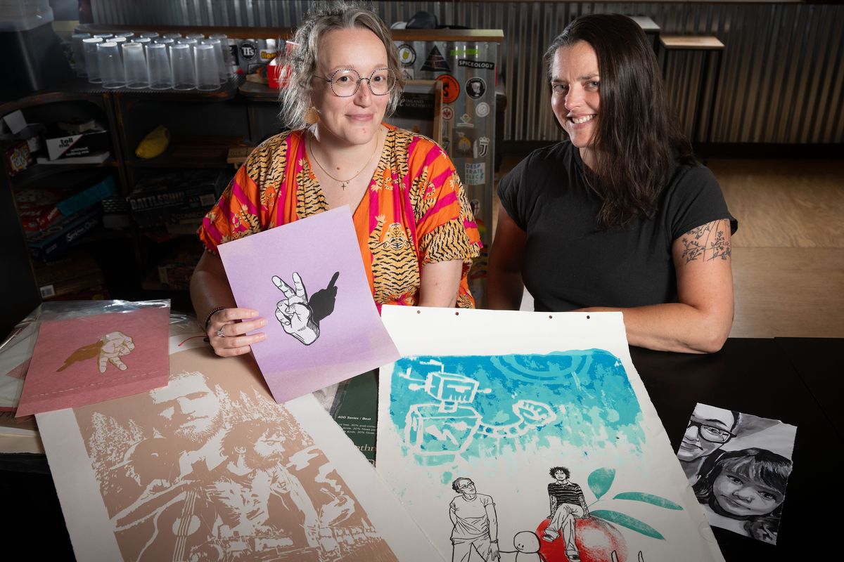 Lindsey Merrell, left, with friend Emily Gwinn, shows some of husband Jon Merrell’s illustrative artwork at Spokane’s Hat Trick Brewing, where they plan to hold a “tap party” fundraiser on Aug. 30.  (COLIN MULVANY /THE SPOKESMAN-REVIEW)