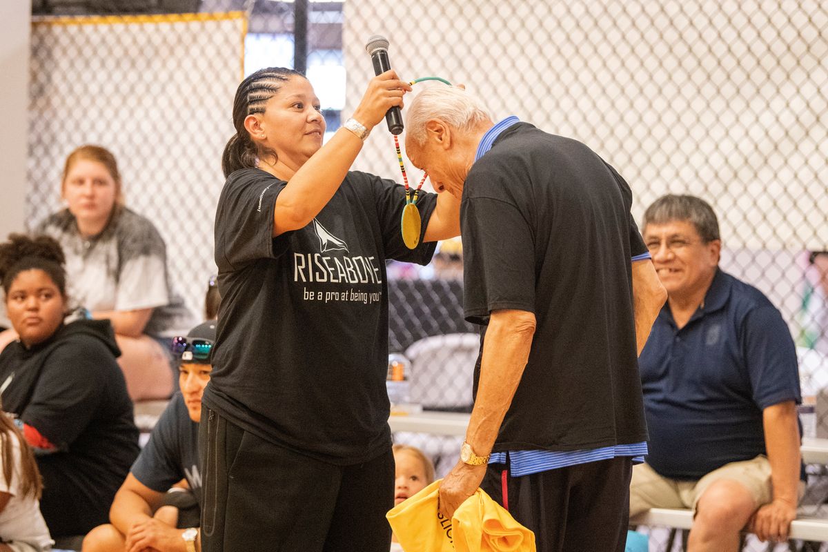 Jaci McCormack, left, places a beaded medallion around the neck of former NBA player and coach Lenny Wilkens Monday, July 12, 2021 at the Hub Sports Center at the end of the Rise Above basketball camp, which she organizes.  (Jesse Tinsley/The Spokesman-Review)