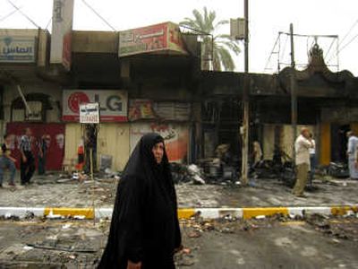 
A woman passes the site of a car bombing in Baghdad on Sunday. The bombing killed six people and wounded seven. A subsequent blast  about a mile away killed two and wounded eight.Associated Press
 (Associated Press / The Spokesman-Review)