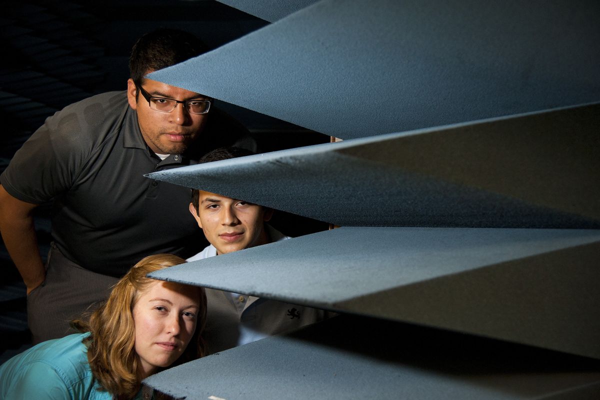 Gonzaga University students, from top: Max Hernandez-Brito, Luis Perez and Caitlin Croskrey stand next to the anechoic chamber in the Smart Antenna and Radio Lab. Below: Croskrey holds a prototype of the smart antenna being developed at GU. (Dan Pelle)