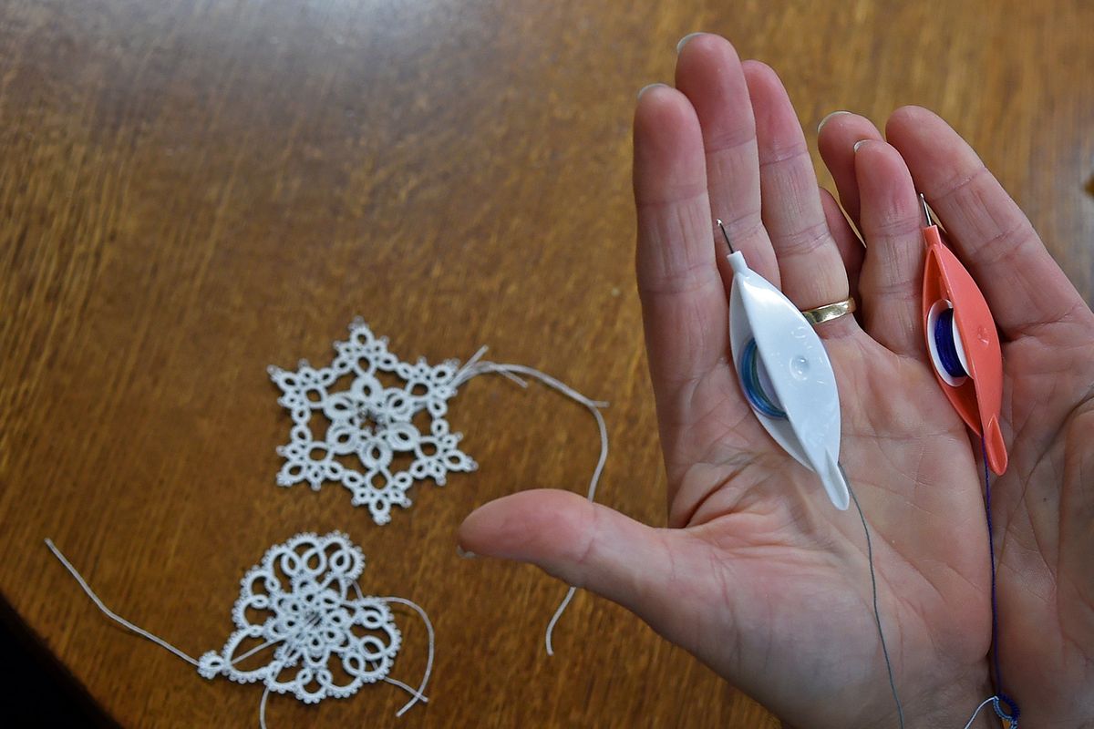 Saralyn Findlay holds the tatting shuttles she used to make the delicate lace pieces on the table. She is a member of the Shuttlebirds Tatting Guild of Spokane.  (Christopher Anderson/For the Spo)