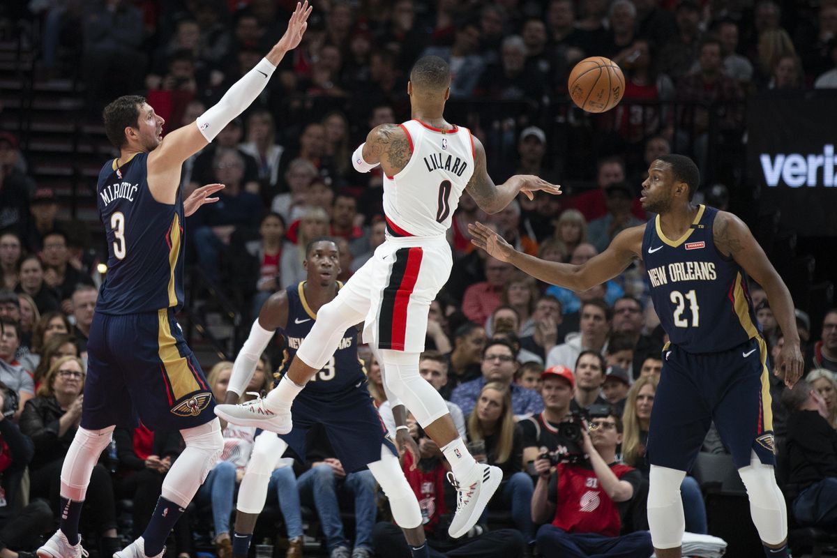 Portland Trail Blazers guard Damian Lillard passes against the defense of New Orleans Pelicans forward Nikola Mirotic, left, and forward Darius Miller during the first half in Game 1 of an NBA basketball first-round playoff series Saturday, April 14, 2018, in Portland, Ore. (Randy L. Rasmussen / Associated Press)