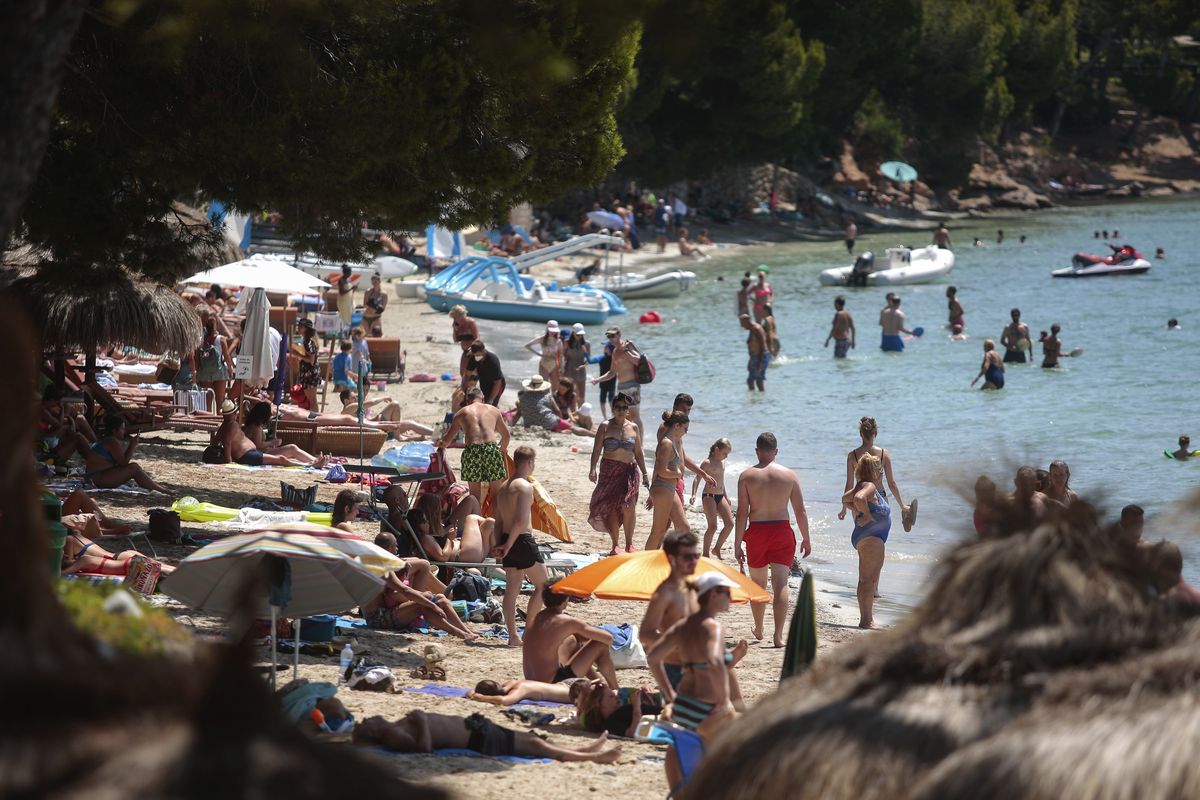 Sunbathers enjoy the beach in Pollença, in the Balearic Island of Mallorca, Spain, Tuesday, July 28, 2020. The U.K. government