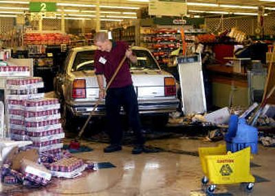
Tidyman's employee Steve Anderson mops up soda in the checkout area at the McKinnon Tidyman's on Wednesday in Spokane Valley. A woman drove through the front of the building after she apparently stepped on the gas pedal when she meant to brake. No one was injured. 
 (Liz Kishimoto / The Spokesman-Review)