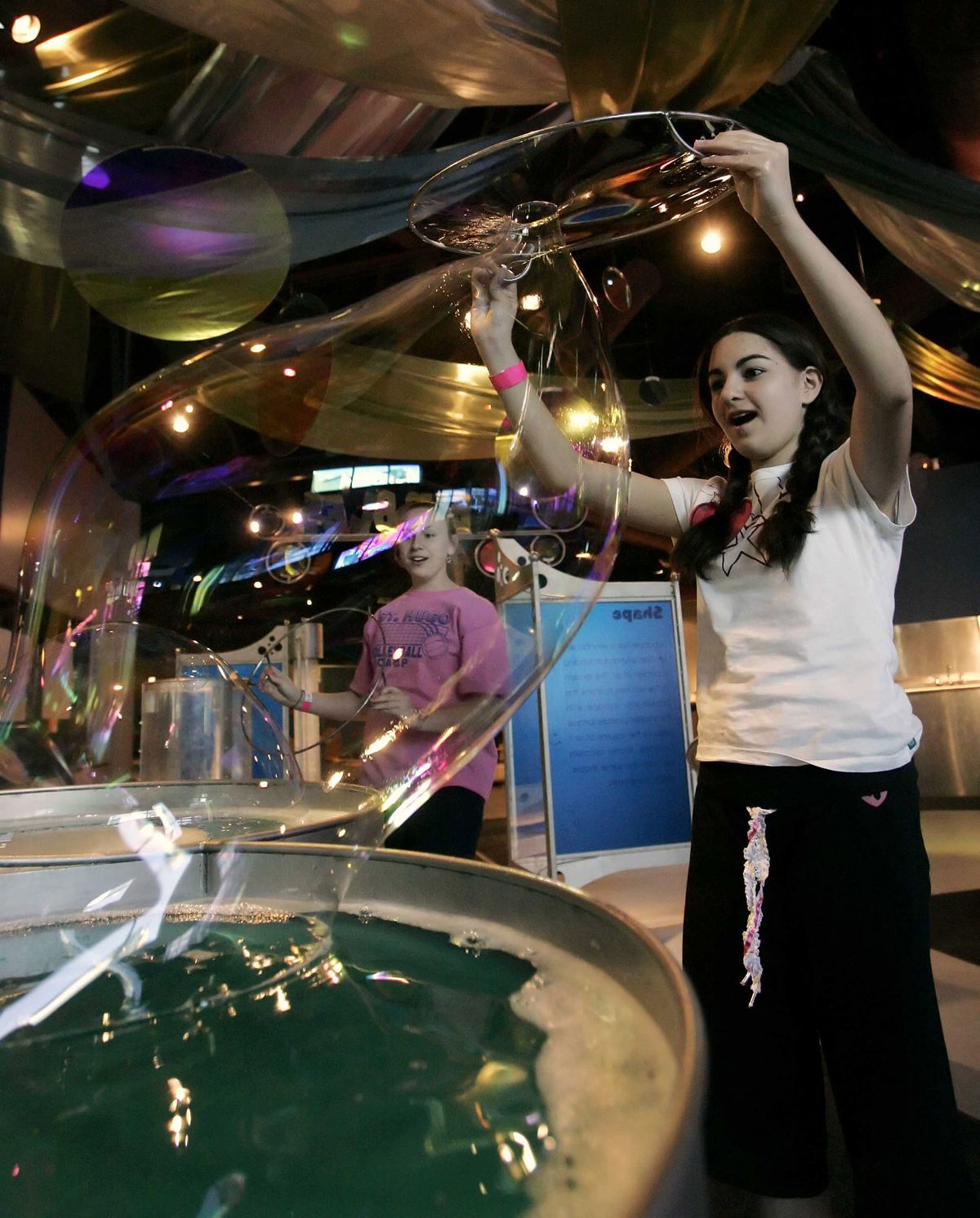 Alicia Carlson, 13, of Bloomfield Hills, Mich., left, and Nicole Farida, 13, of West Bloomfield, Mich.,  play in the bubbles display as they learn about surface tension in 2006 at  what is now called Imagination Station in Toledo, Ohio. (Toledo) Blade (Dave Zapotosky (Toledo) Blade)