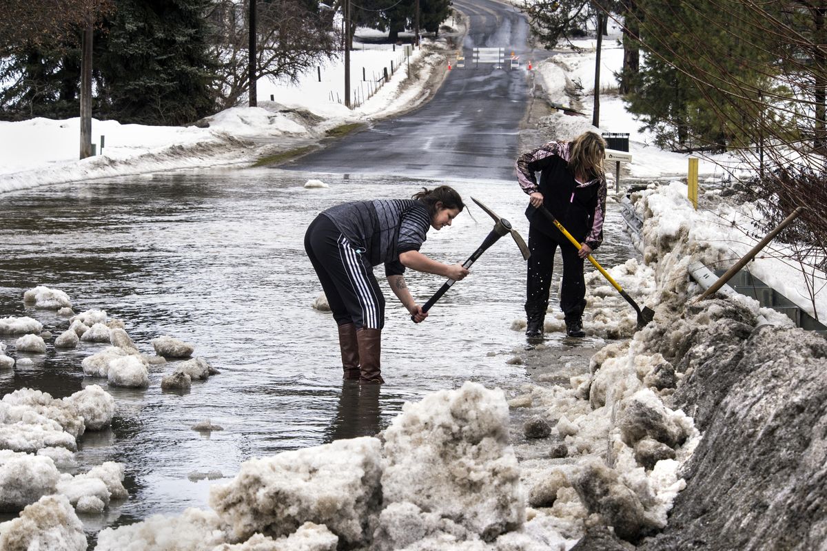 Leah Jordan, left, and her mother-in-law Jerri Jordan, use pick axe and shovels to cut away at a snow and ice berm over the flooding Little Deep Creek on Colbert Road, Feb. 17, 2017, in Colbert, Wash. The women live adjacent to the creek and Jerris basement was flooding. (Dan Pelle / The Spokesman-Review)