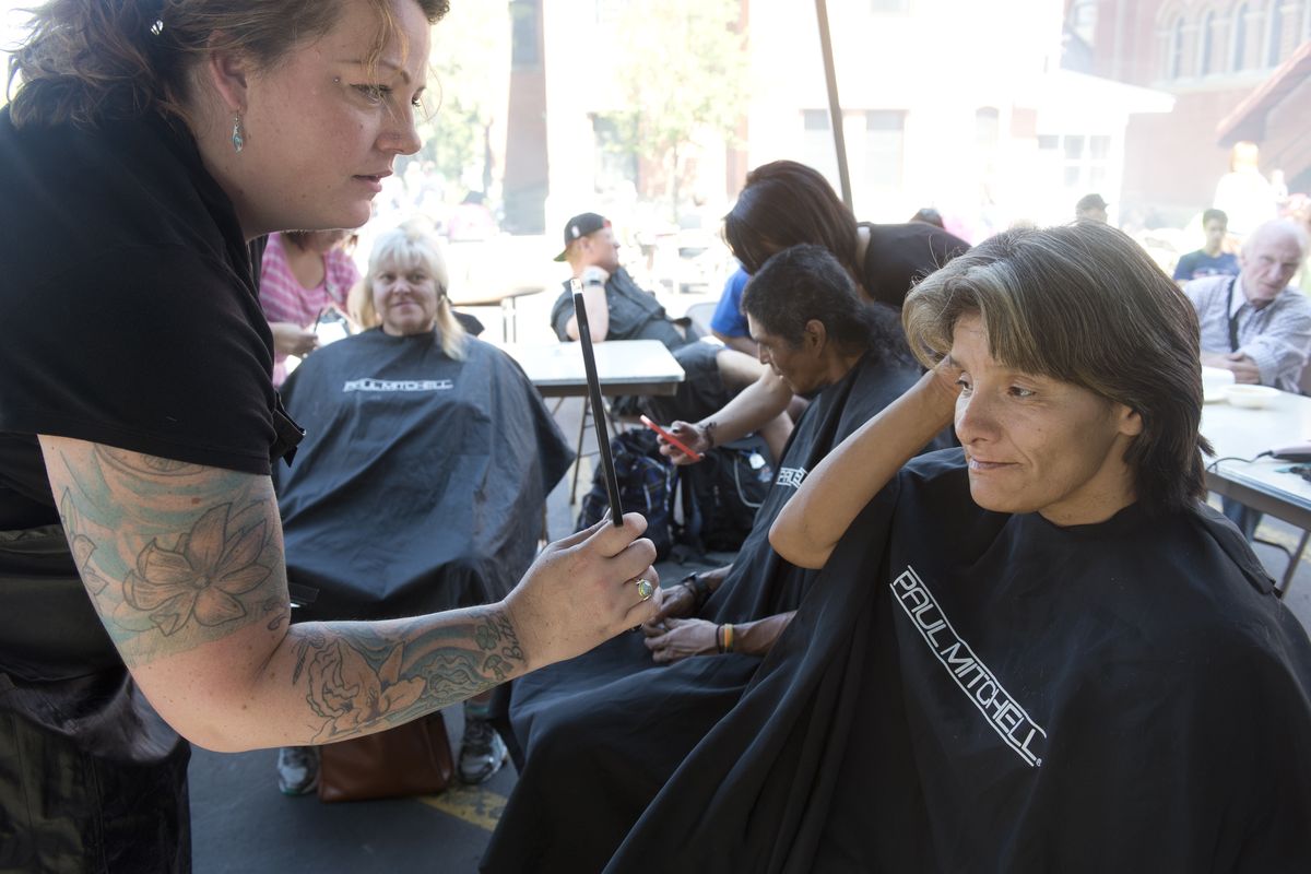 Nikki McFadden, right, checks out her new haircut from volunteer stylist Tosh Swain at the annual barbecue hosted by the Cathedral of Our Lady of Lourdes on Tuesday in Spokane. The church fed the needy with barbecued hamburgers, and students from the Paul Mitchell school gave free haircuts. Those in attendance also could receive free veterinarian care for their pets. (Jesse Tinsley)