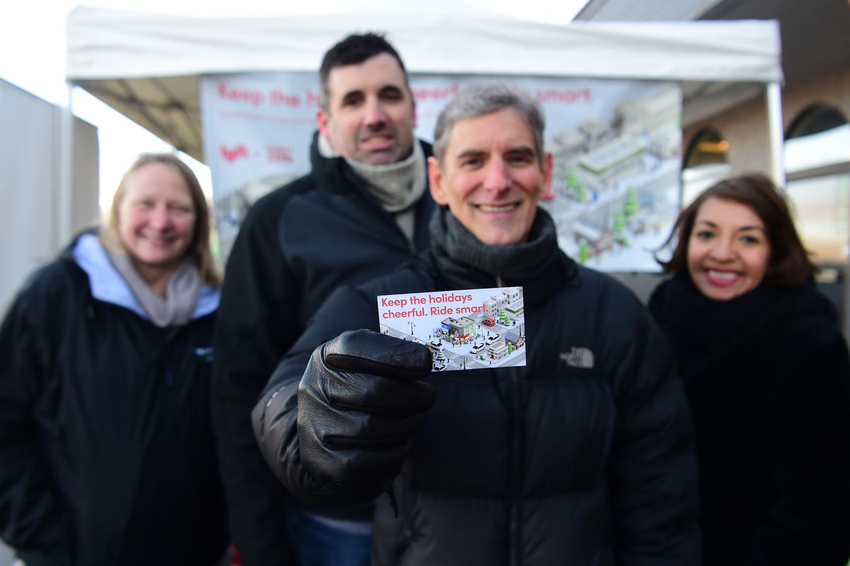 Vivian McPeak, producer of Seattle’s Hempfest, holds out a card good for a $20 credit on the rideshare app Lyft, which he and partners from the Washington Traffic Safety Commission were handing out in front of Satori, a South Hill pot shop Wednesday, Dec. 12, 2018. From left, they are Shelly Baldwin and Mark Medalen from the Washington Traffic Safety Commission, McPeak, and Erika Mascorro, a Spanish speaker who was there to help talk with Spanish speakers about not using marijuana and driving during the holidays. (Jesse Tinsley / The Spokesman-Review)