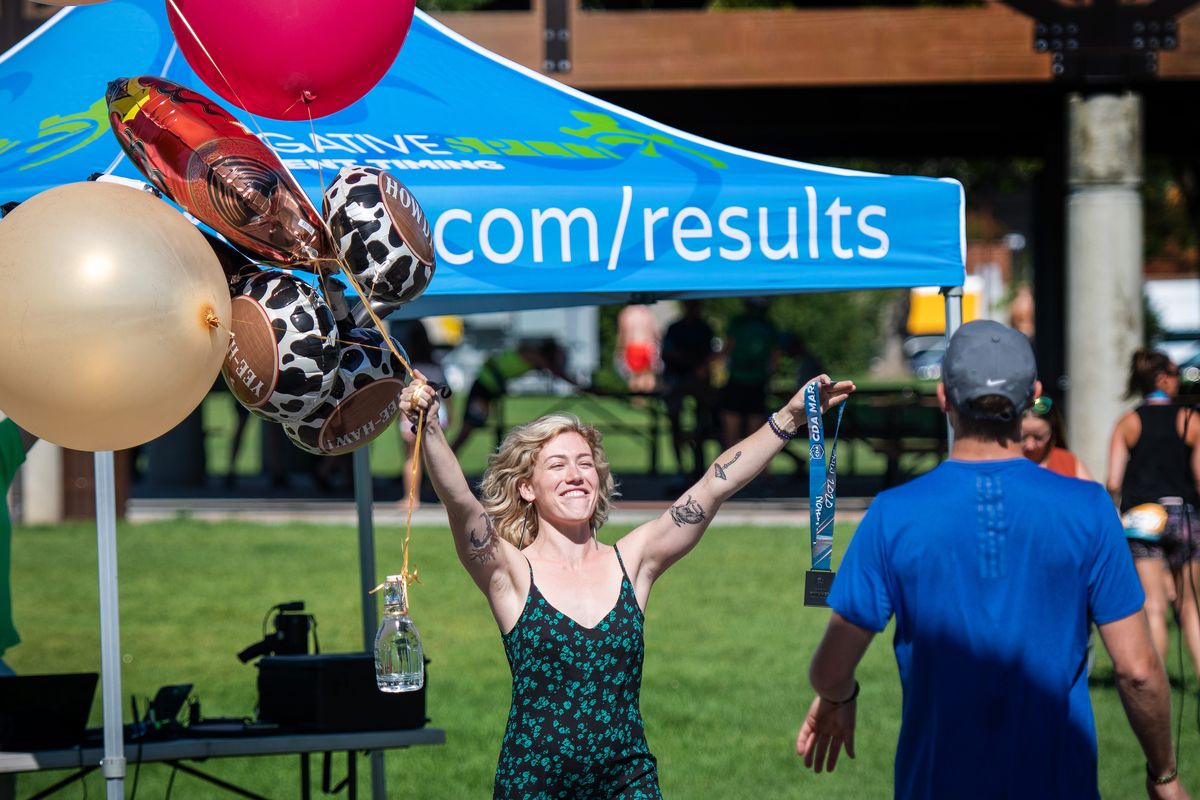 Carli Bjerke greets her boyfriend, Lucas Cole, with balloons and a medal as he finishes the socially distanced Coeur d’Alene Marathon in McEuen Park on Saturday.  (Colin Mulvany/THE SPOKESMAN-REVIEW)