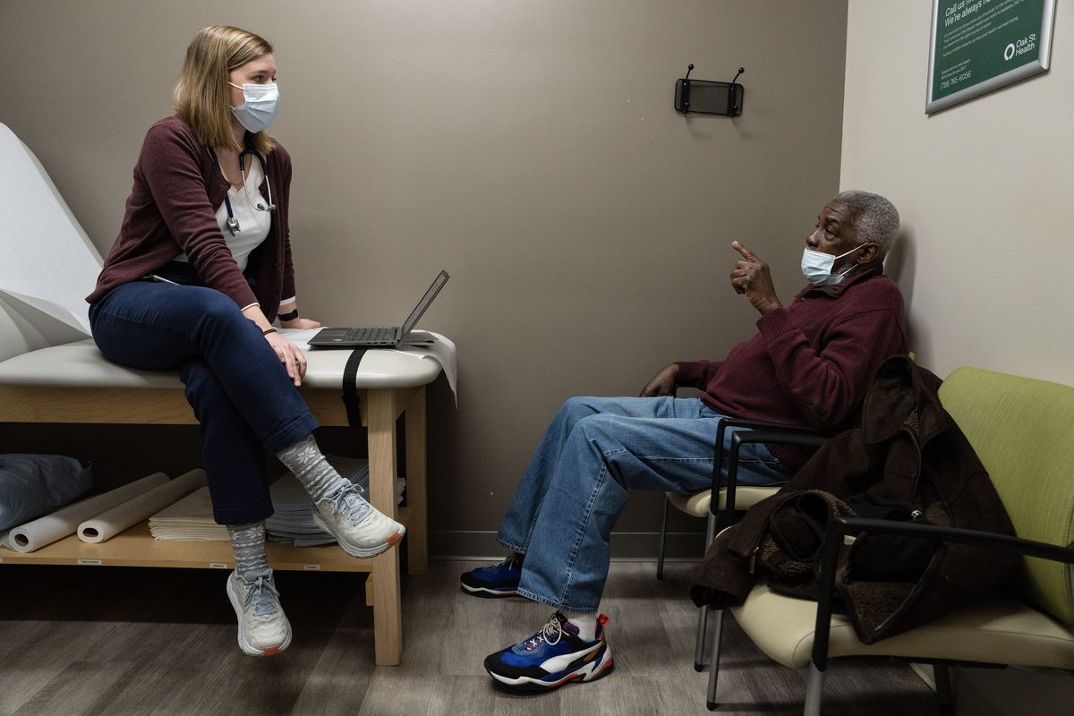 Dr. Haley Lynn, left, attends to a patient, Nathaniel Brookard, at Oak Street Health in Brooklyn, Feb. 22, 2023. Large health insurers and other companies are especially keen on doctors